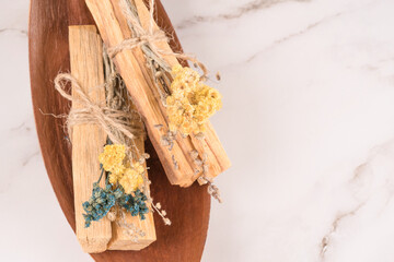 Incense for yoga practice, meditation and spiritual practices. Palo santo sticks with dried flowers over white marble table background with copy space for text
