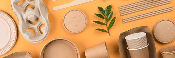 Banner with eco-friendly paper tableware - kraft paper food packaging on orange background. Street...