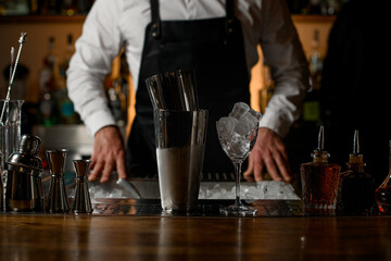 close-up of shaker cups and glass with ice and other bar equipment on a bar counter