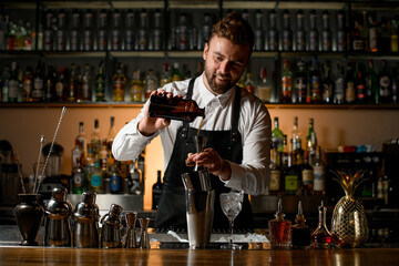 view of the bar with shakers and bottles, and the bartender pours a drink from a bottle into a jigger