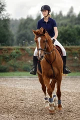 Gordijnen Equestrian sport -young girl rides on horse. © Linas T