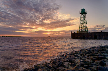 scenic sunset over the mouth of the river Weser with the silhouette of a historic lighthouse in Bremerhaven