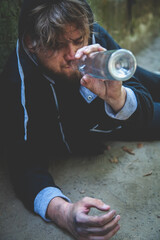 Portrait of young alcoholic man drinking vodka. Alcoholism, pain, pity, homelessness, social problem of dependence concept.