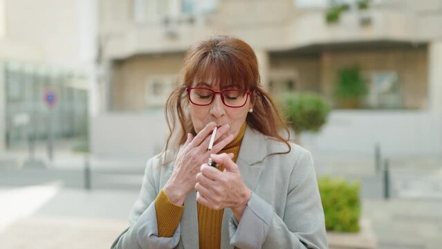 Middle age woman business executive smoking cigarette at street