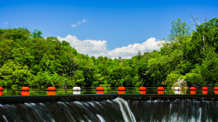 Buoys near dam edge in beautiful spring day with green trees and blue sky © miro