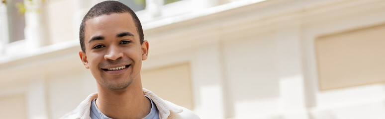 Obraz premium young and happy african american man smiling in urban city, banner.