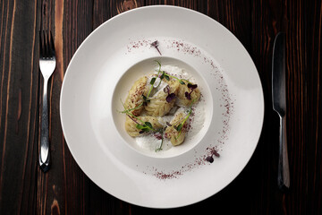 kurze dish on a plate, with a fork and a knife on a wooden background with spices