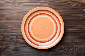 Top view of empty orange plate on wooden background. Empty space for your design