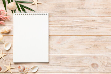 Blank writing book with summer beach accessories on background, copy space. Flat lay with copy space