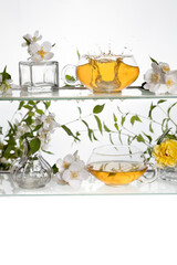 Jasmine tea on a glass shelf .Two transparent cups with green tea and white flowers and splash.