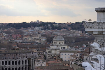Fototapeta na wymiar ROME, ITALY - February 05, 2022: Panoramic view around the Colosseum in city of Rome, Italy. Cold and gray sky in the background. Macro photography of the green parks with the old buildings.