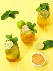 Mojito or virgin mojito long rum drink with fresh mint, lime juice, cane sugar and soda. On yellow background.