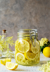 Elderberry infused water or syrup made with fresh flowers and lemons as basic ingredients. Grey background