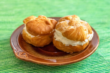Eclairs with cream. Profiteroles on a plate. Photo
