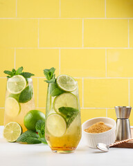Mojito or virgin mojito long rum drink with fresh mint, lime juice, cane sugar and soda. On yellow background.