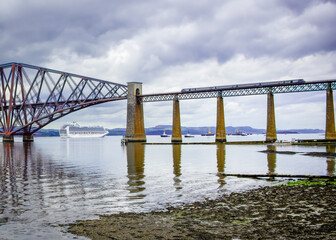 Southside of Forth bridge with a train passing over and liner through the arch