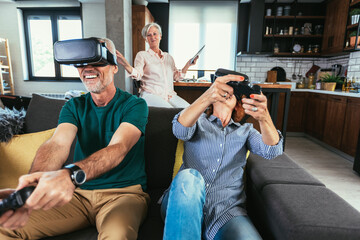 Group of middle age friends smiling happy playing video game with VR glasses at home.