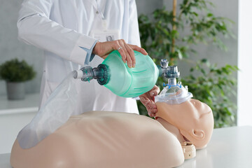 Close-up of healthcare worker using oxygen mask for respiration while practicing on dummy - Powered by Adobe