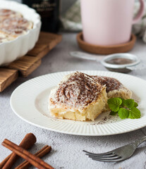 Sweet homemade buns with cream cheese and cinnamon on a white plate with mint decor from cinnamon sticks