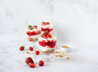 Italian strawberry tiramisu dessert with mascarpone and whipped cream, savoyardi crumb and fresh strawberry in glass on marble. Recipe of simple dessert, cheesecake, pudding or berry trifle cake.