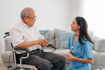 Fototapeta premium Young asian caregiver smiling and talking to aged man while taking care of him.