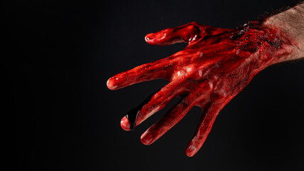 Close-up of a male hand stained with blood on a black background. 