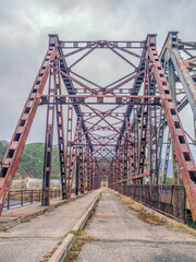 Old steel bridge across the river. Perspective of inside view.