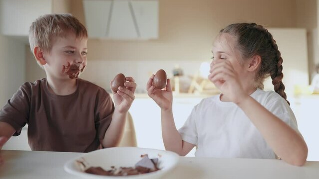baby boy and girl eat chocolate. dirty little baby kids in the kitchen eating chocolate in the morning. happy family eating sweets kid dream concept. baby dirty face eating chocolate lifestyle cocoa