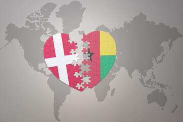 puzzle heart with the national flag of guinea bissau and denmark on a world map background. Concept.