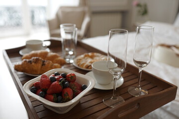 Delicious breakfast in bed. Coffee in bed on a white bed with buns, berries on a white