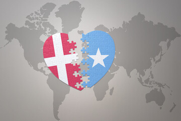 puzzle heart with the national flag of somalia and denmark on a world map background. Concept.