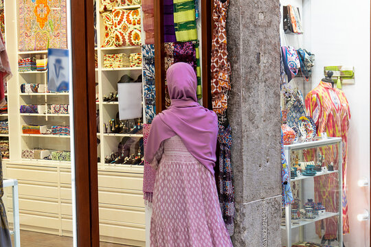 Mujer musulmana entrando en tienda de ropa y textiles árabes