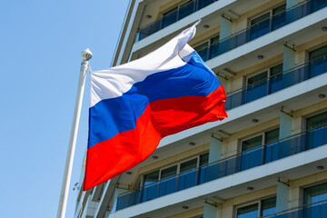 The flag of Russia is flying against the background of the building