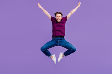 Full length photo of young guy have fun jump up energetic wear casual clothes isolated over violet color background