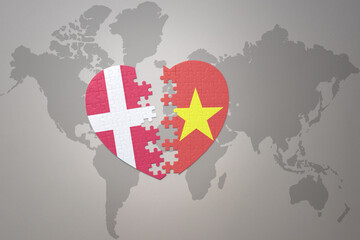 puzzle heart with the national flag of vietnam and denmark on a world map background. Concept.