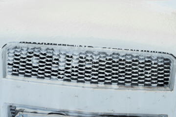 Front grill of a white car through which water with soap falls for the cleaning of the vehicle.