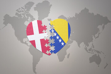 puzzle heart with the national flag of bosnia and herzegovina and denmark on a world map...