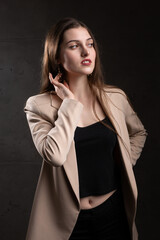 Portrait of a young brunette with long hair in the studio. Dramatic photo in dark colors.