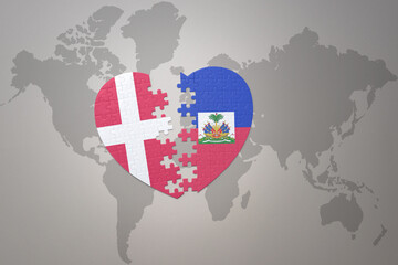 puzzle heart with the national flag of haiti and denmark on a world map background. Concept.