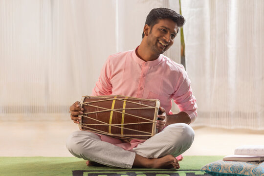 Portrait of young man playing Dholak at home