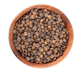 French lentils in wooden bowl, isolated on white background. Dry puy lentil grains pile. Top view.