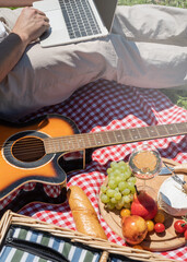 unrecognizable man in white pants outside having picnic and using laptop, working outdoors
