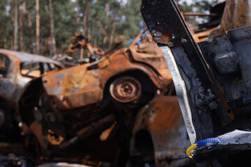 Fototapeta na wymiar bracelet as symbol of ukraine - flag from blue and yellow with burnt out cars on background from russian attack. russian military war crimes against ukraine. glory to ukraine