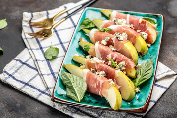 Appetizer with pear, blue cheese and prosciutto ham on a dark background, Healthy fats, clean eating for weight loss, Long banner format. top view
