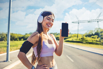 Woman training outdoors and using a smartphone to monitor her fitness progress. Young sports woman taking rest and checking results on smartphone app after urban work out.