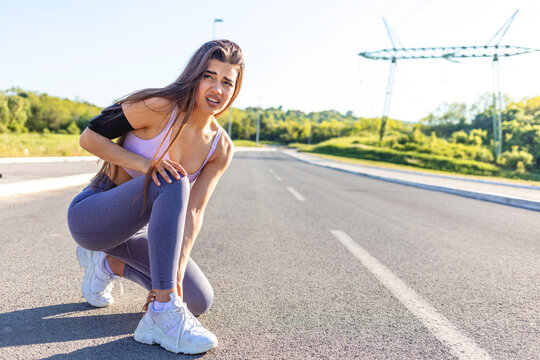 Young sports women having pain / injury during exercise and jogging in the nature. Female runner athlete leg injury and pain. Woman suffering from painful leg while running in the park.