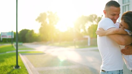 Daughter runs to dad and hugs him. Father picks up the child in his arms.