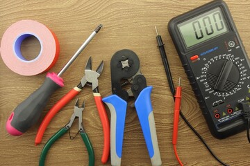 Multimeter and mounting tools on a wooden background close-up.