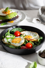 Breakfast with fried eggs and vegetables in a pan