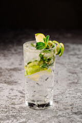 Transparent cocktail with lime in glass on black background
